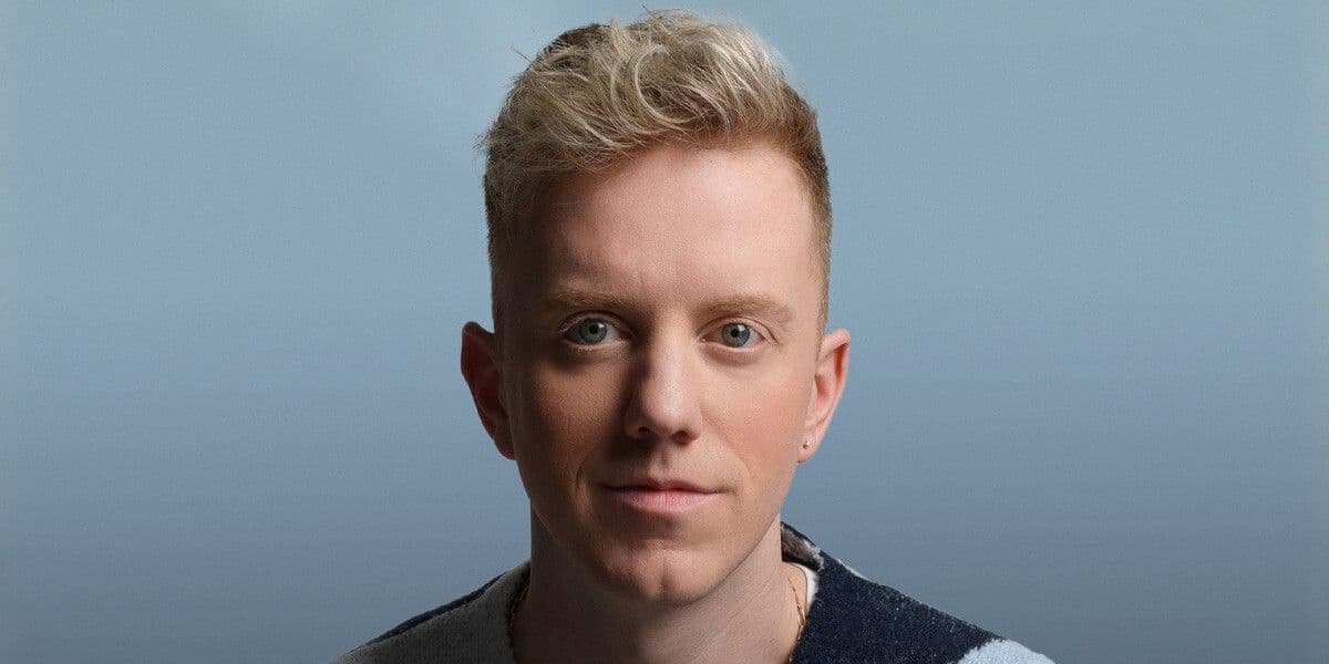 James Barr wears a blue cardigan with a neutral expression